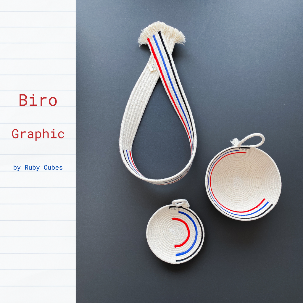 Three objects from the Biro Graphic collection feature in this image - a textile wall hanger, a textile vessel and textile tray. The colour is neutral with a black, blue and red motif reminiscent of biro pens.